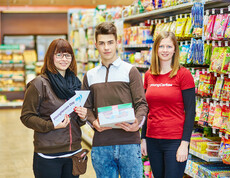 Eine youngCaritas-Mitarbeiterin steht neben zwei Mitarbeitern des Spar in Ybbs. Die Frau hält einen Pfeil, wo "youngHeroes" oben steht und der auf den männlichen Mitarbeiter zeigt.