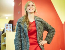 Eine Frau in einem roten Kleid und grauen Jacke der carla Amstetten